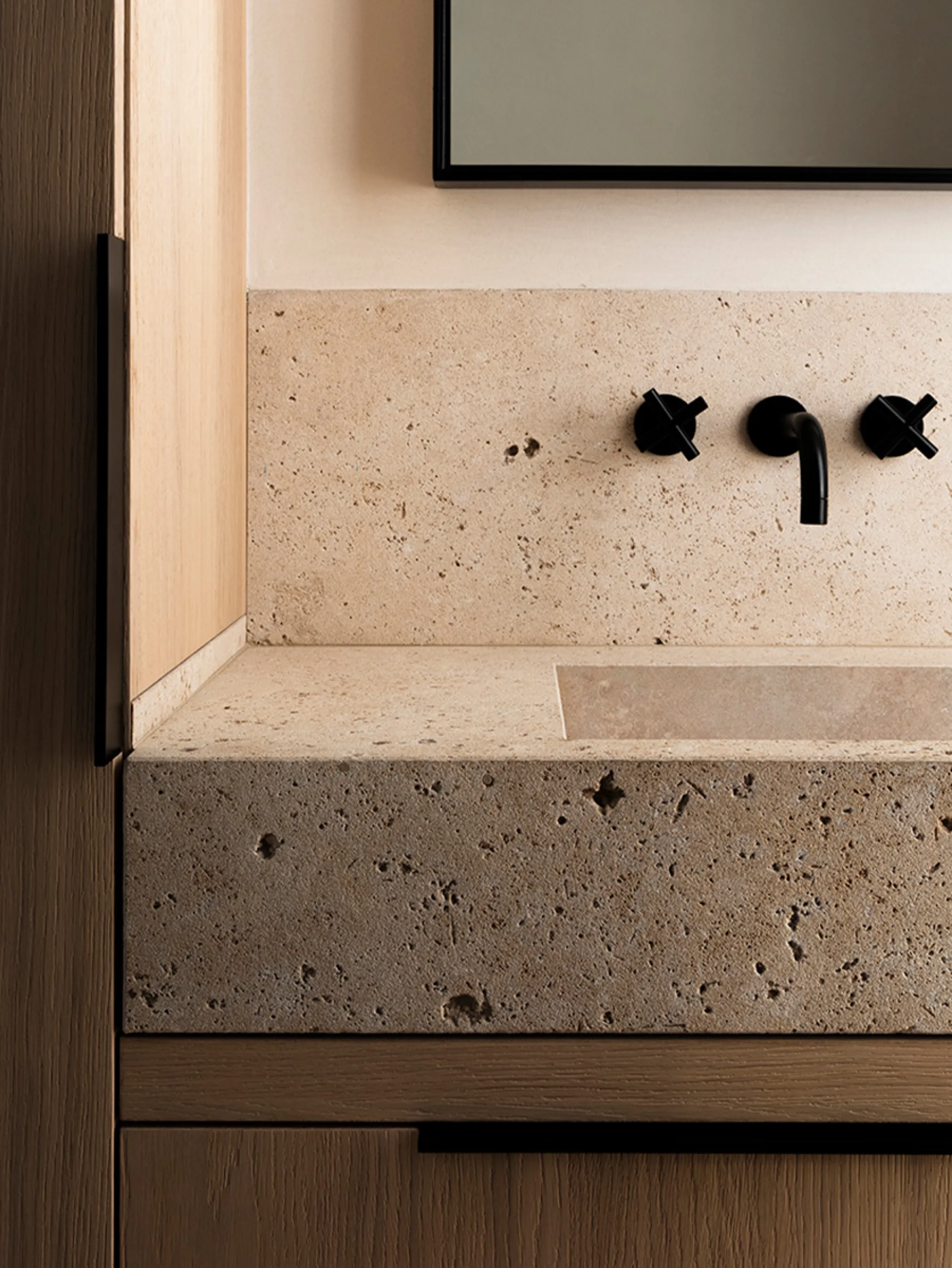 Stone bathroom sink on a wood vanity, with highly tactile surfaces.