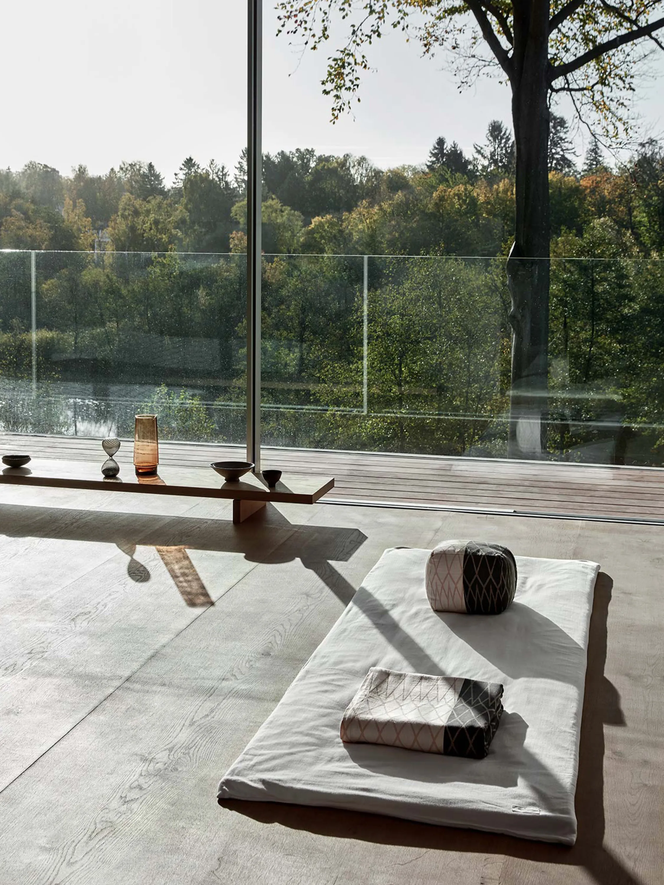 Meditation space on a room with a fully glazed wall and a view onto nature.