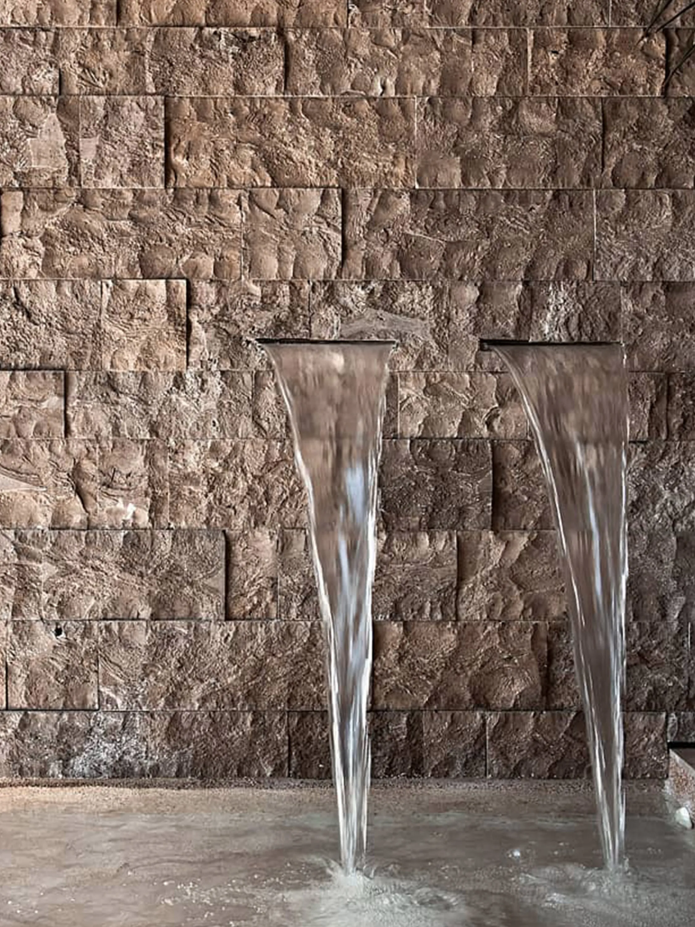 Stone wall with water jets flowing out of it.
