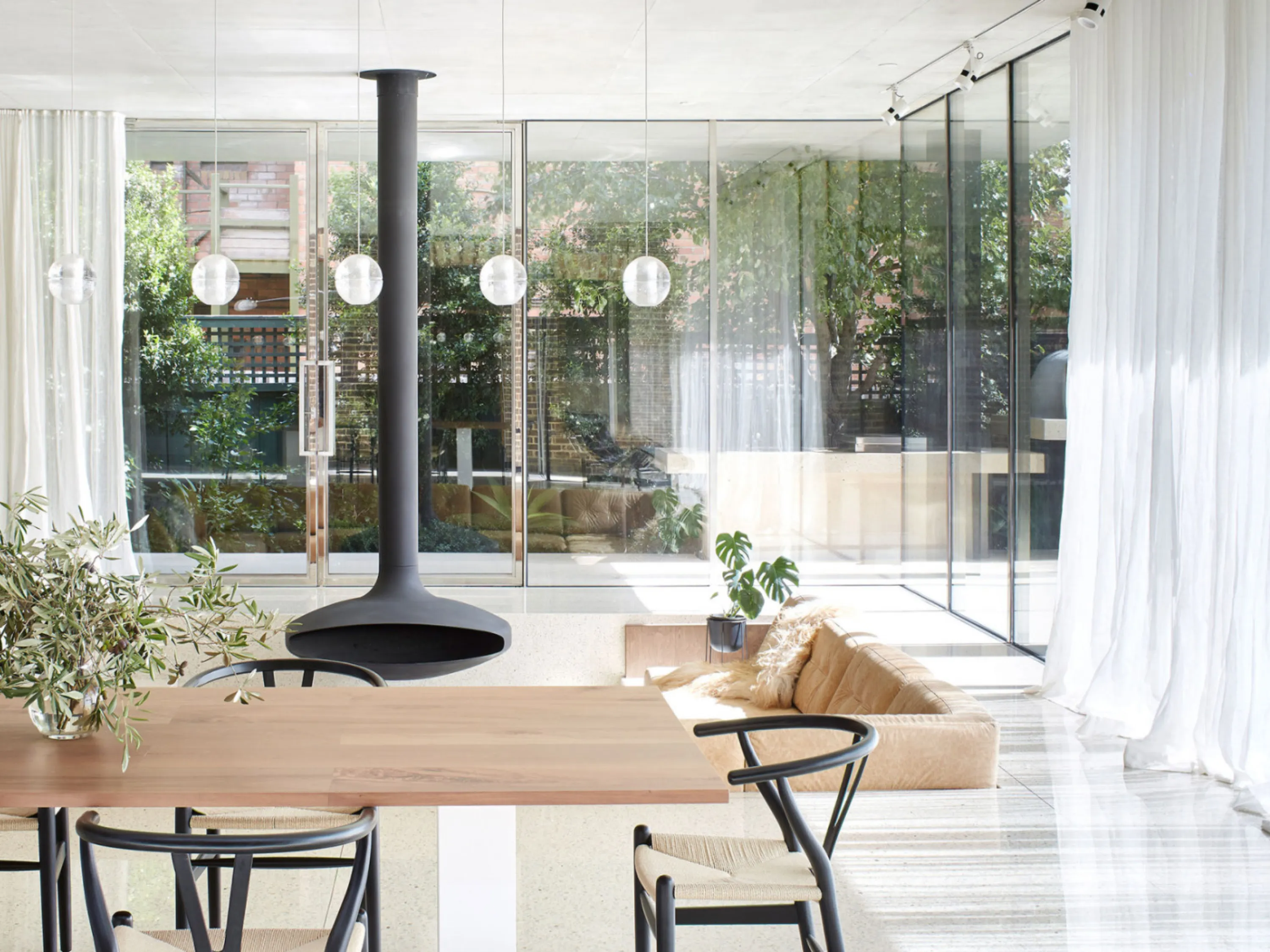 Living-dining area with glazed walls and a garden outside.
