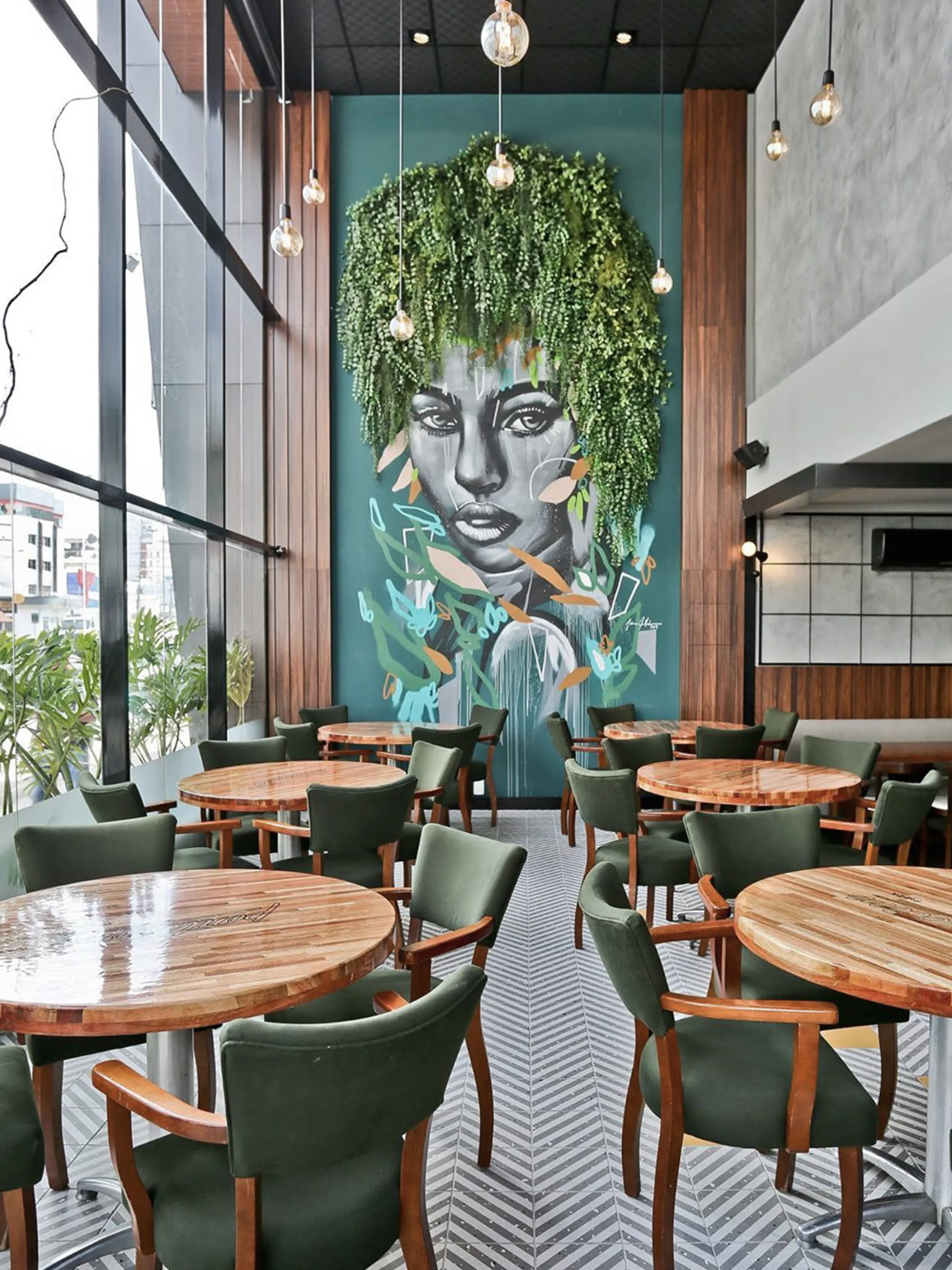 Restaurant with draping plants acting as the hair of a face drawn on the wall.
