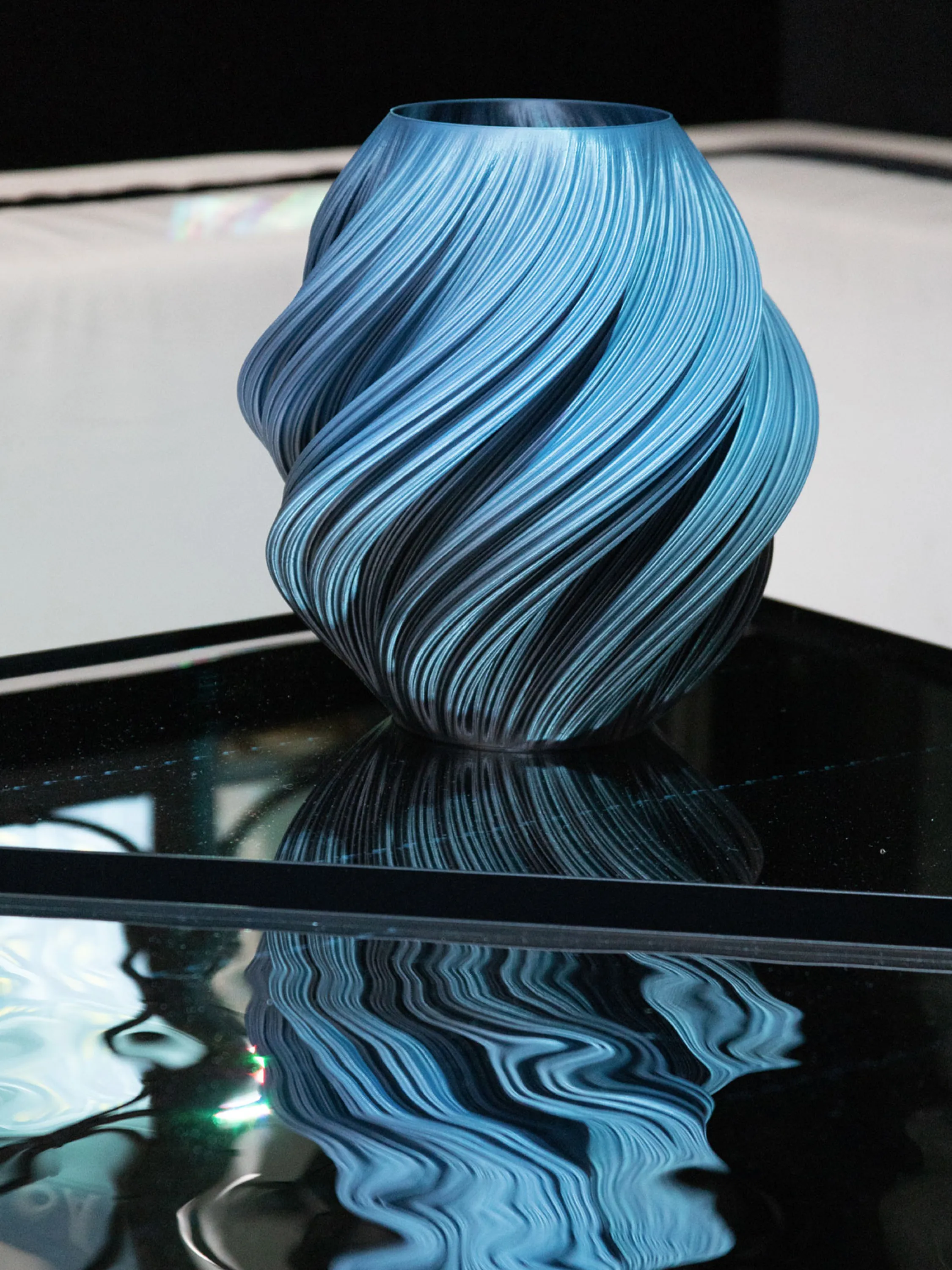 Vase with a wavy texture reflecting on a water-like mirrored surface.