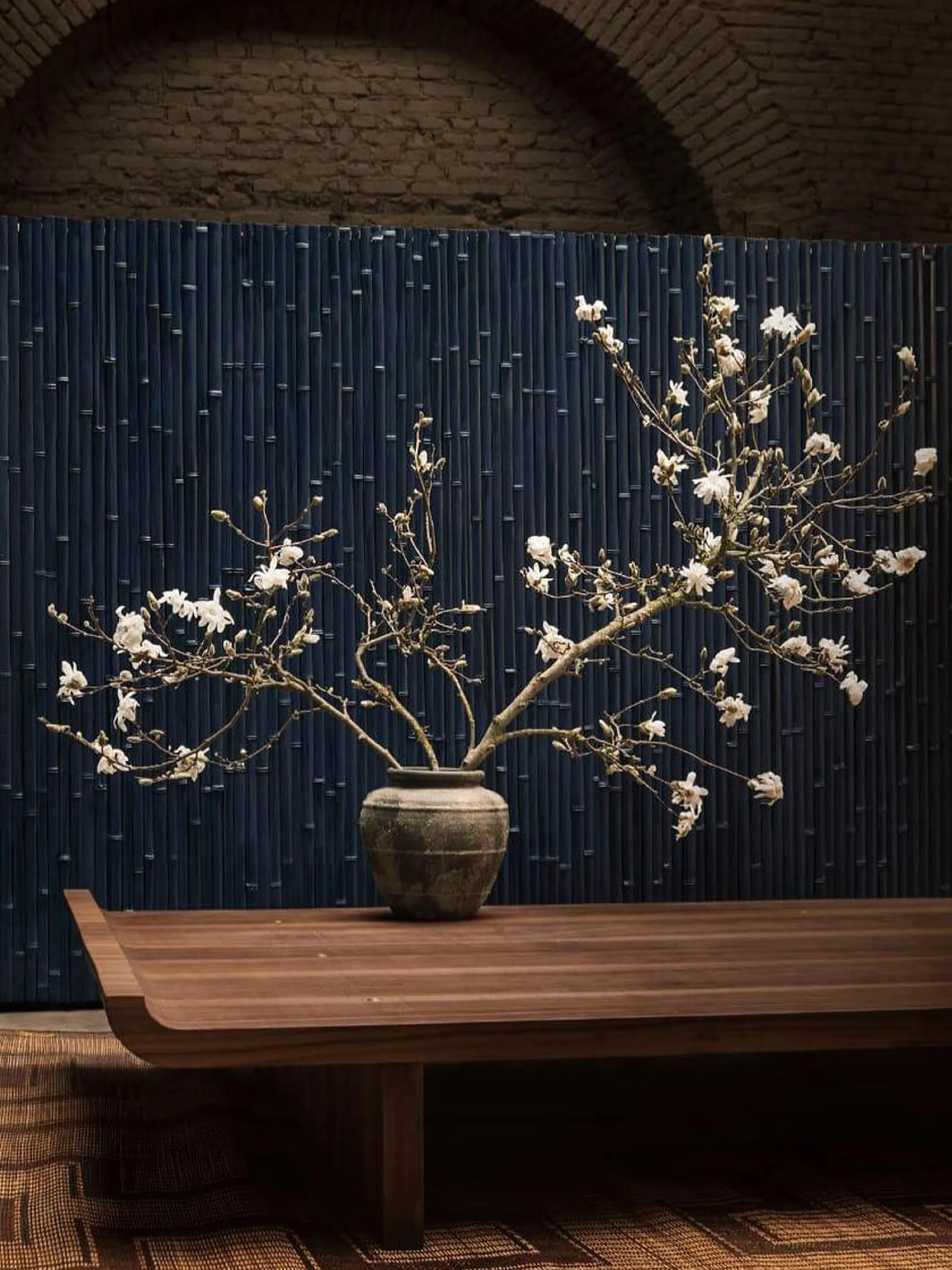 Oversized flower arrangement against a deep blue bamboo screen.