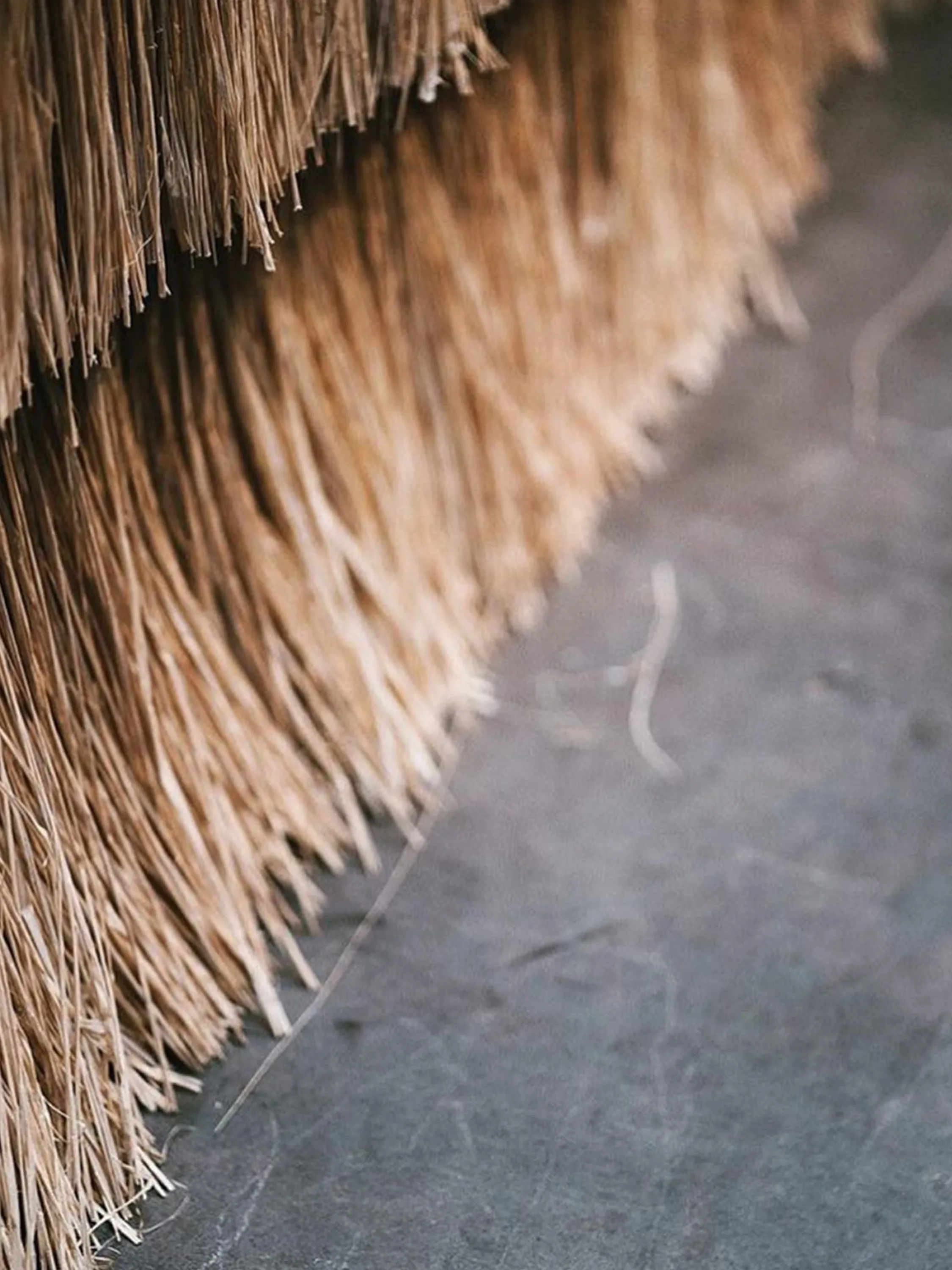 Close-up of a straw room divider on a concrete floor.