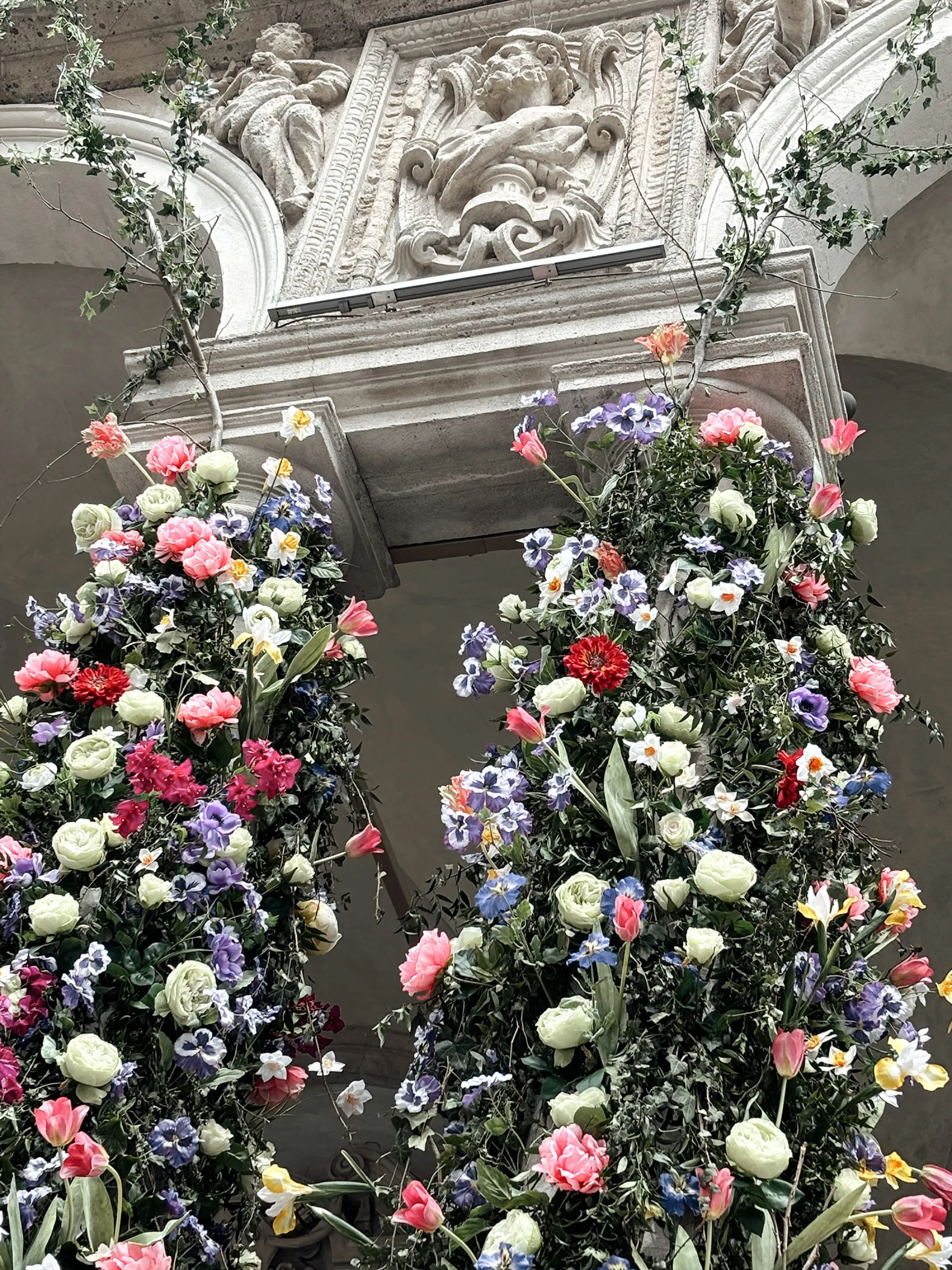 Flowers adorning the columns of a historical building.