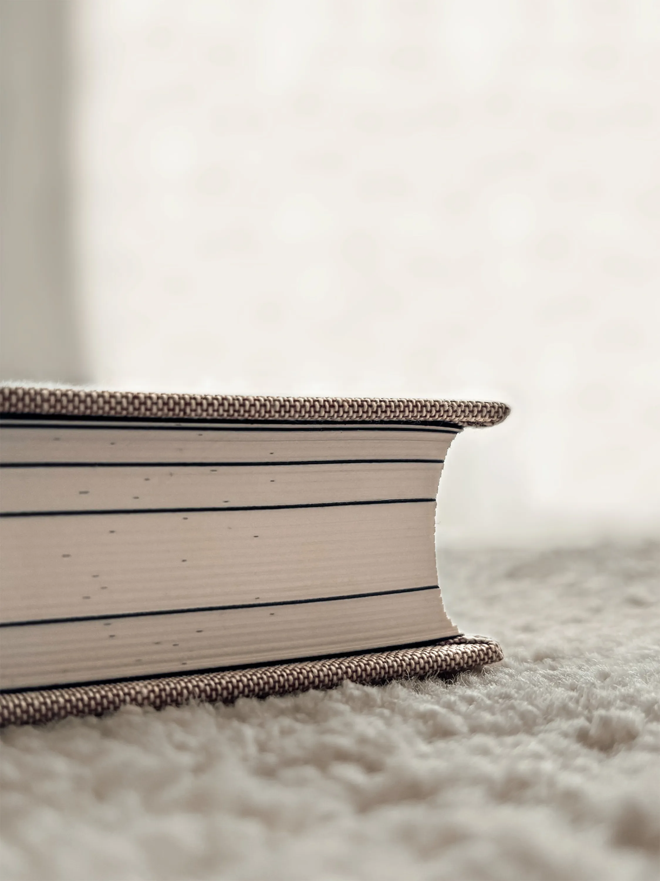 Book resting on a textured rug. Detail of the book's side.