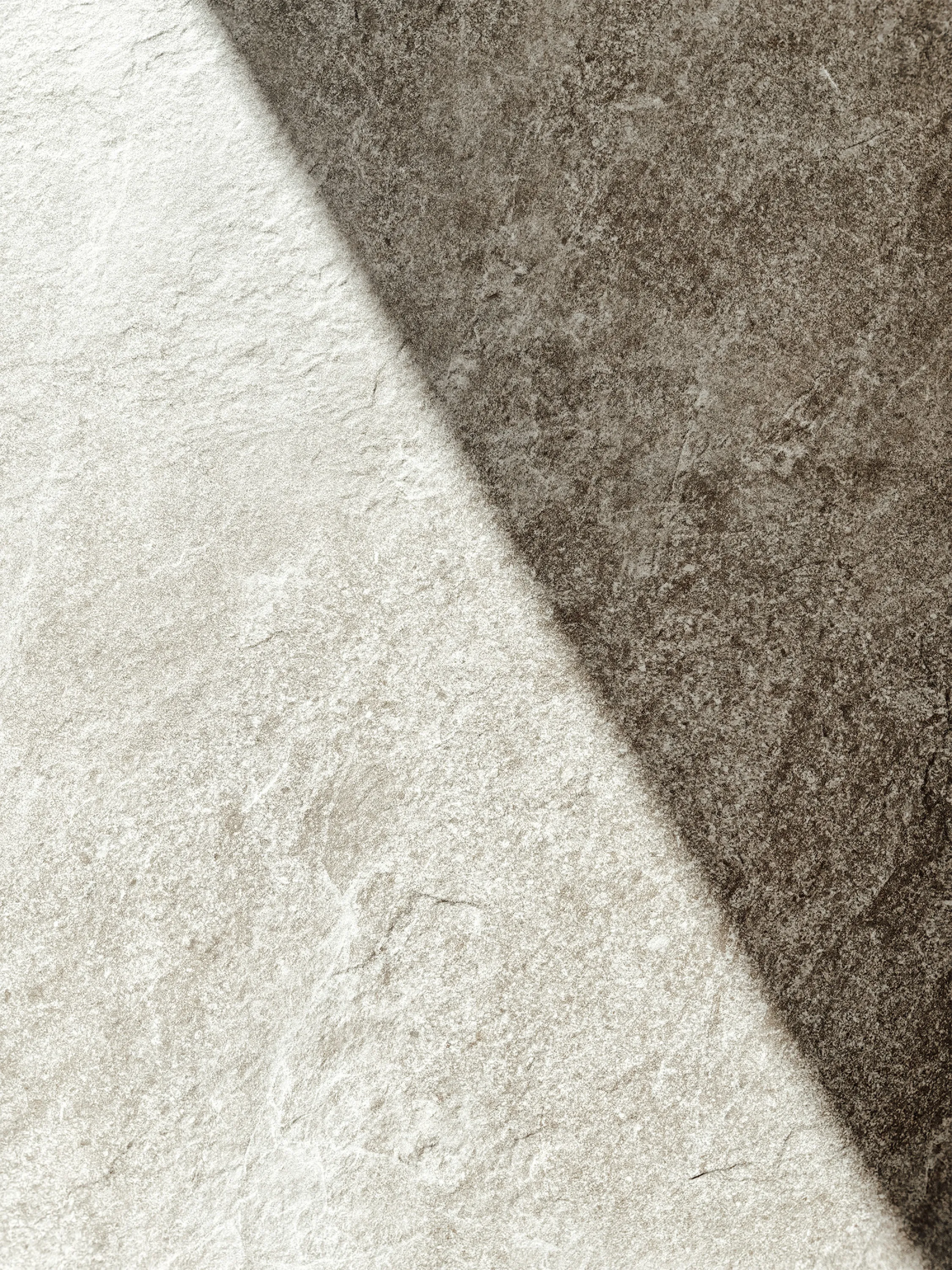 A stone floor divided by a sharp line between bright sun and deep shadow.