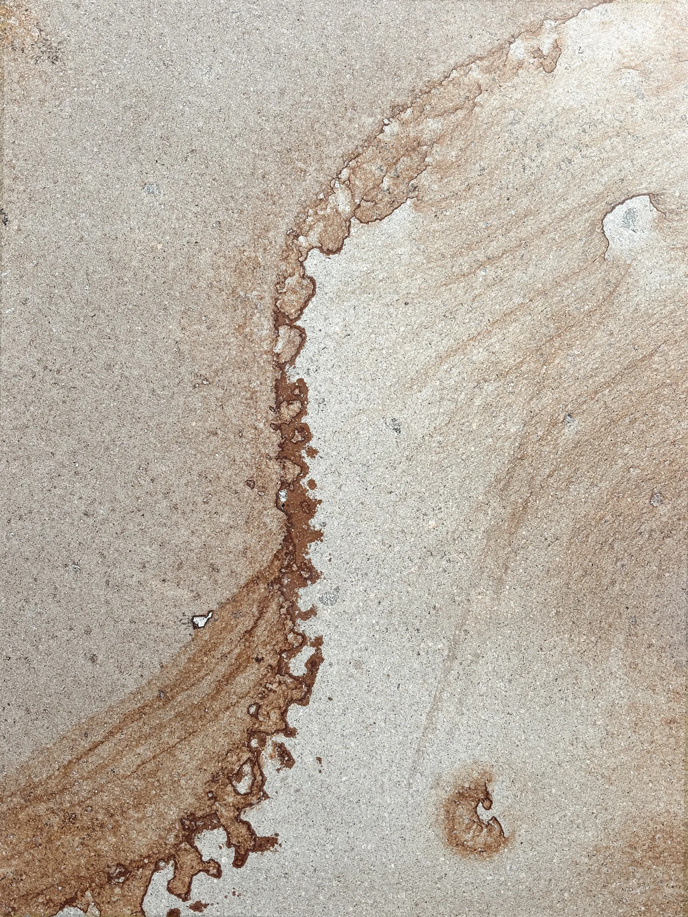 A stone floor with a rust-toned mineral stain spreading across pale ground.