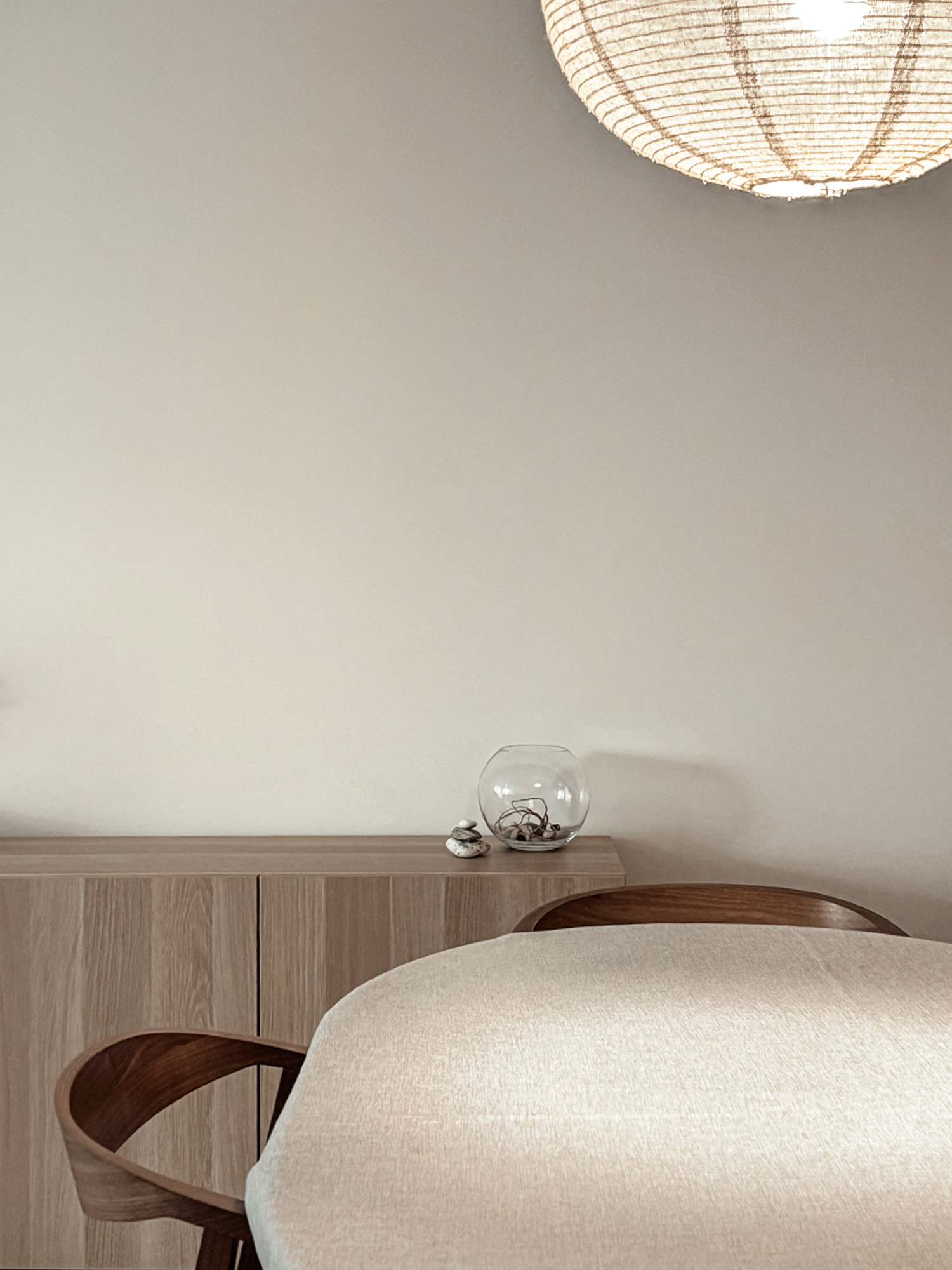 Dining area with oval table, curved-back chairs, oak sideboard, and a textile pendant