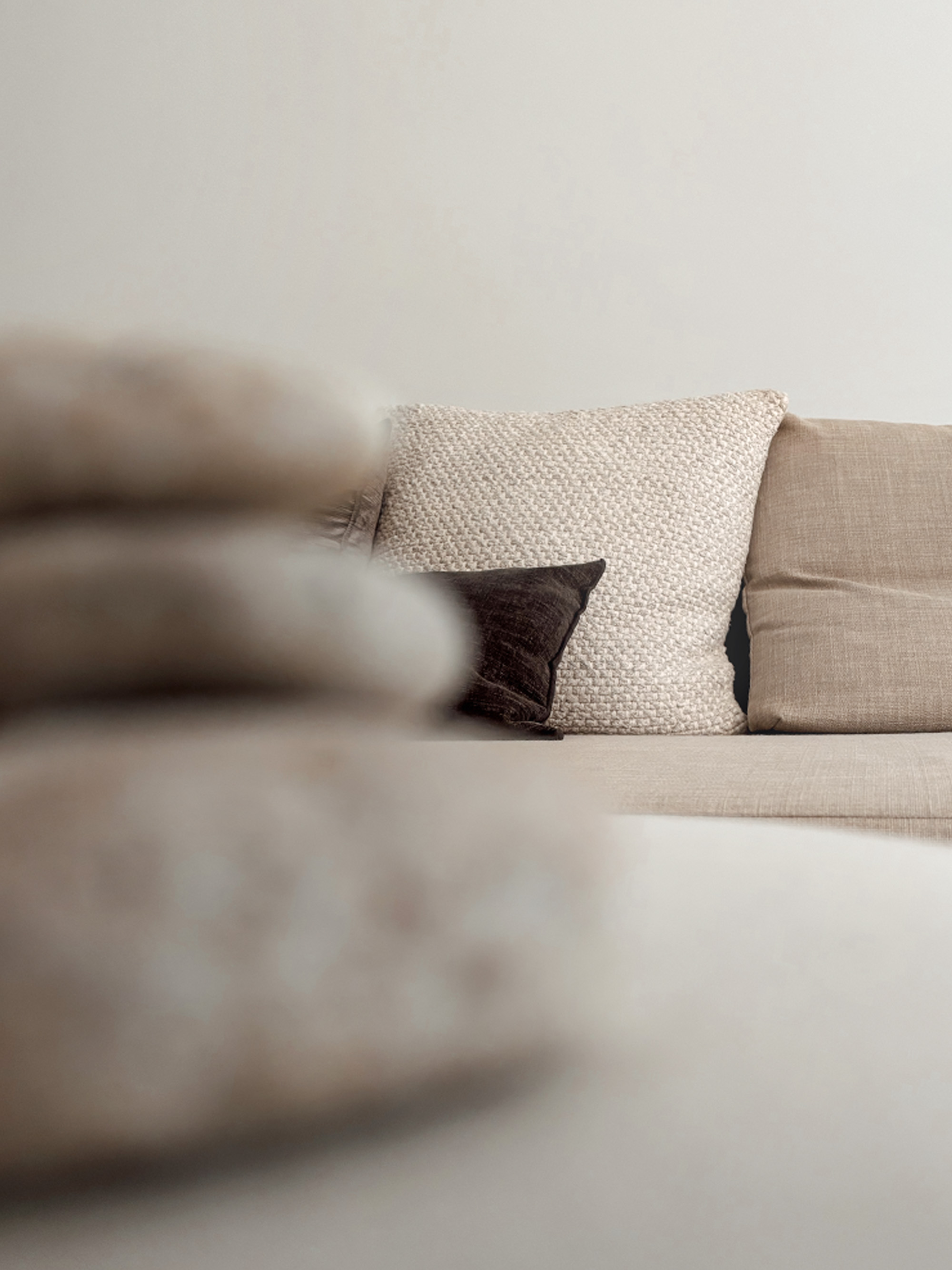 Layered cushions in cream and dark velvet on a light beige sofa