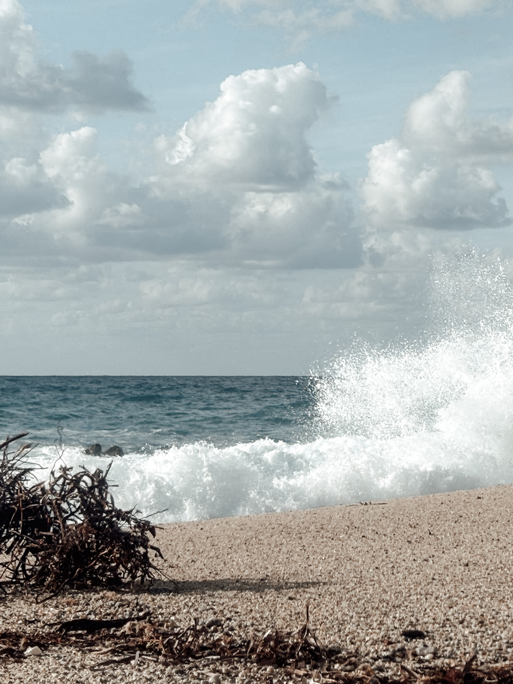 A wave breaking on the shore under a clouded sky